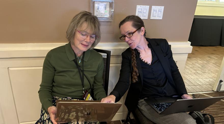 Two researchers holding laptops collaborating